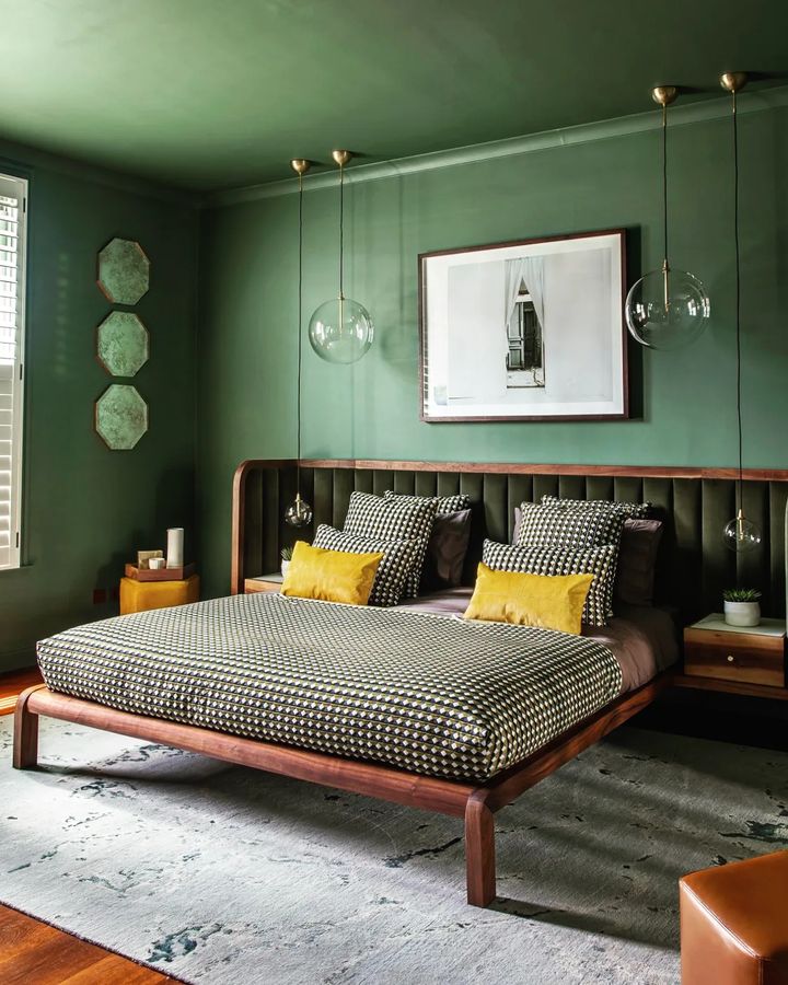 A green bedroom with a neutral bed positioned squarely against the wall. Photo by Instagram user @aetherhealth.