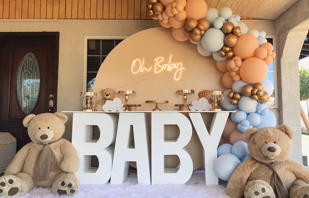 A teddy bear sits next to a large baby-themed table. Photo by Instagram User @reyespartyrentals_.