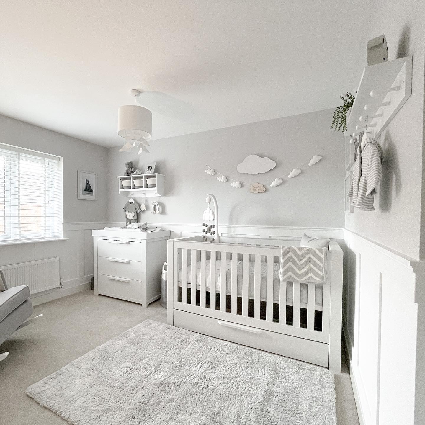 Gray nursery with cloud-themed wall decor behind the crib. Photo by Instagram user @jessicalouise.home. 