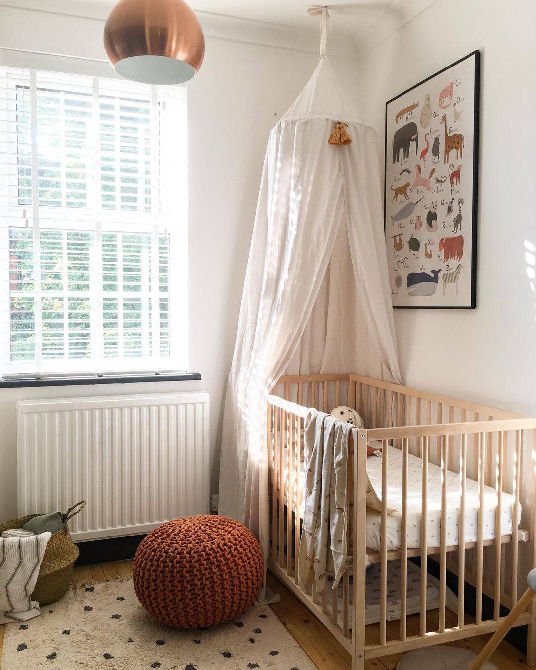 Crib with minimal bedding and white canopy. Photo by Instagram user @down_and_decor