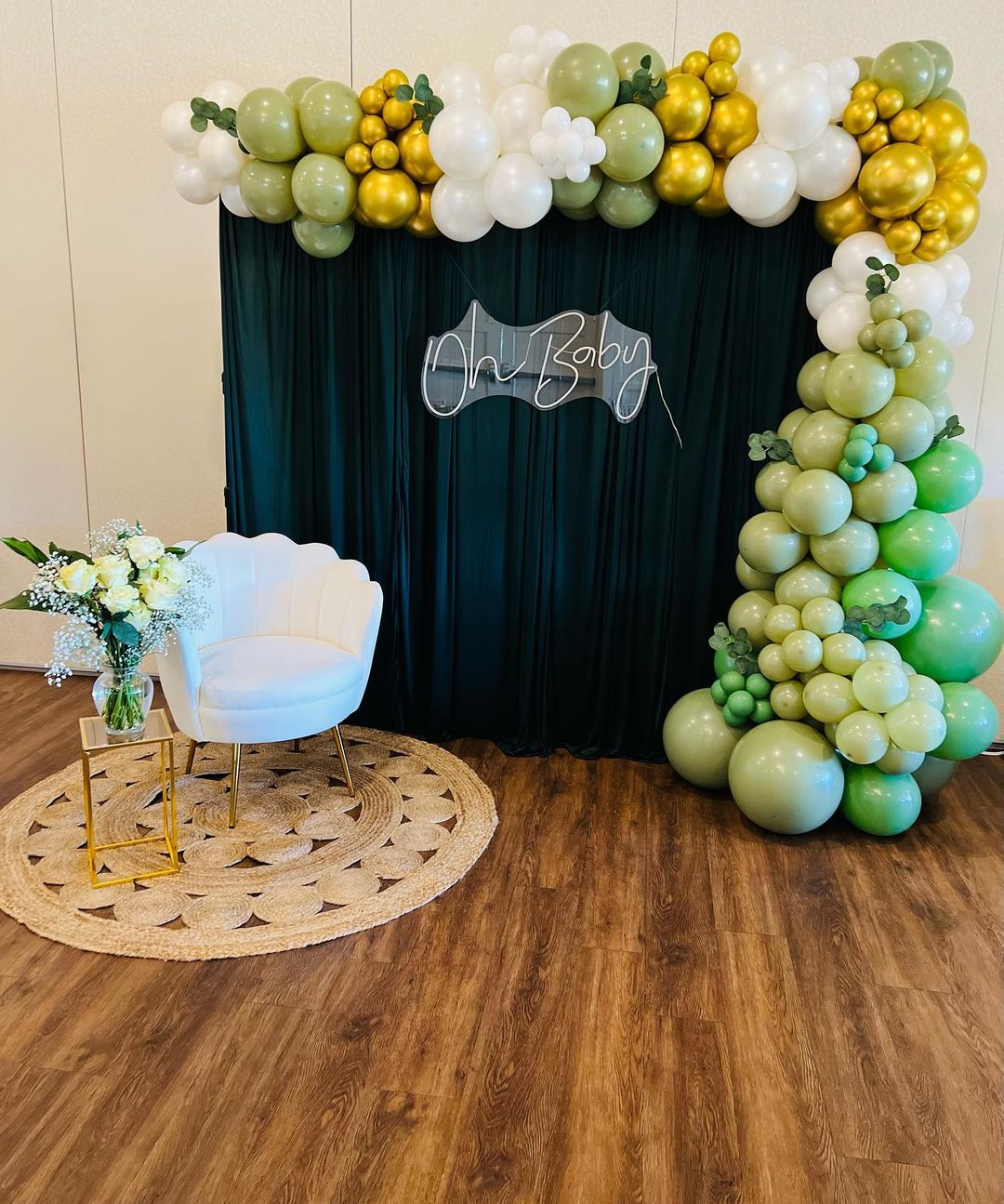 Green balloons surround a curtain. Photo by Instagram user @sweetcastles_events.
