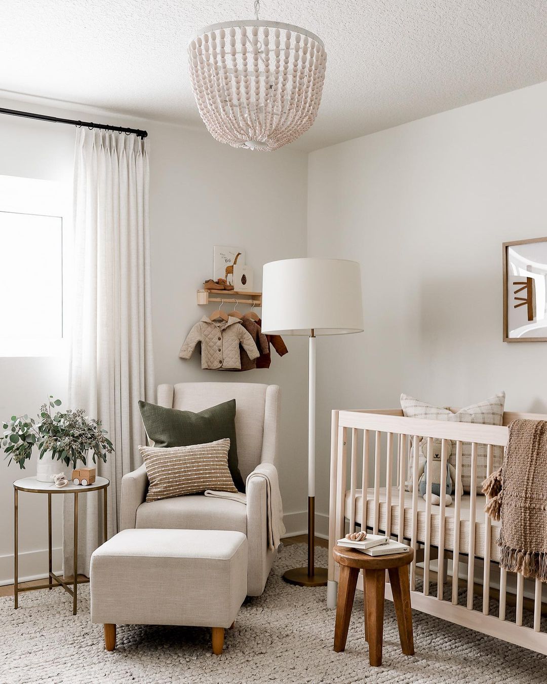 Neutral baby room with nursing chair and wooden stool. Photo by Instagram user @halfway_wholeistic