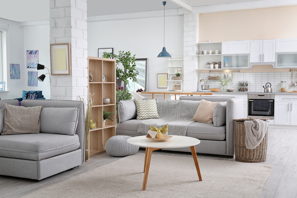 A spacious, well-lit apartment living room with a view into the kitchen.