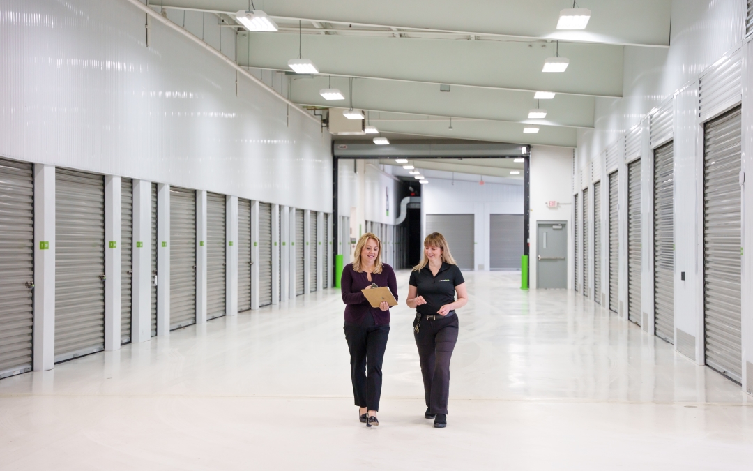 Two people walking between rows of self storage units.