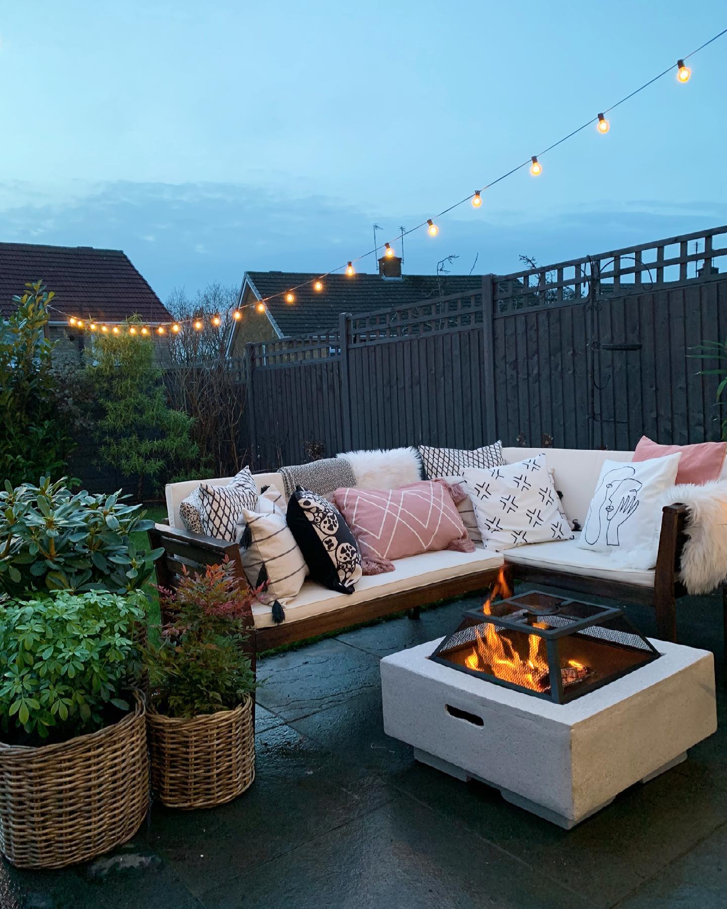 fire pit on outdoor patio with seating and lights at night. Photo by Instagram user @mo.and.the.jungle.shelf