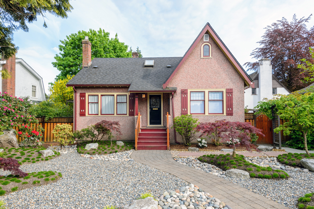 The facade of a red house with a gravel yard and pavers leading up to the house