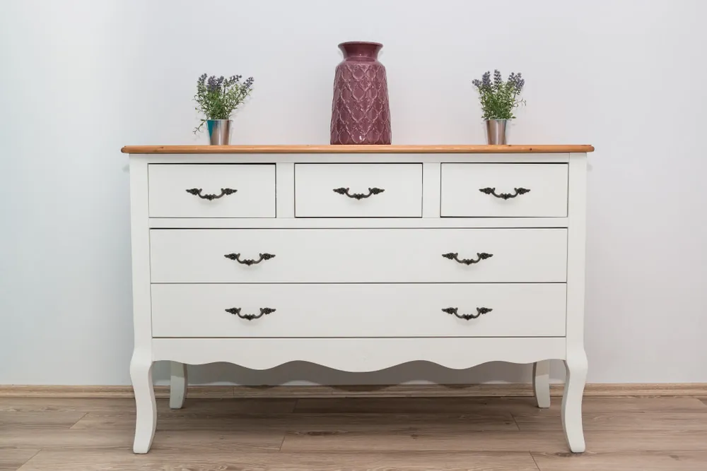 A white antique dresser with decorations on top