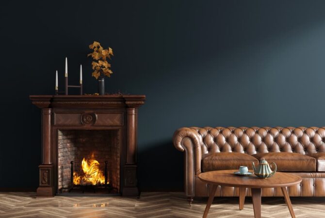 A room with black walls, a fire place, and a brown leather couch