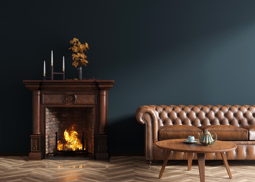 A room with black walls, a fire place, and a brown leather couch