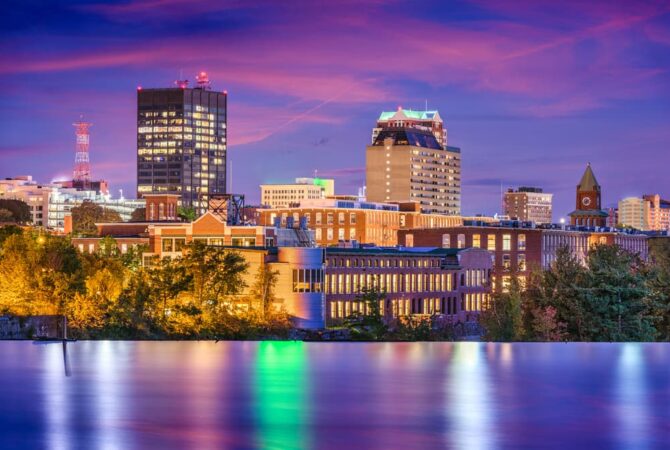 Image of downtown Manchester, NH skyline at twilight. Featured Image for Best Neighborhoods in Manchester for Singles & Young Professionals.