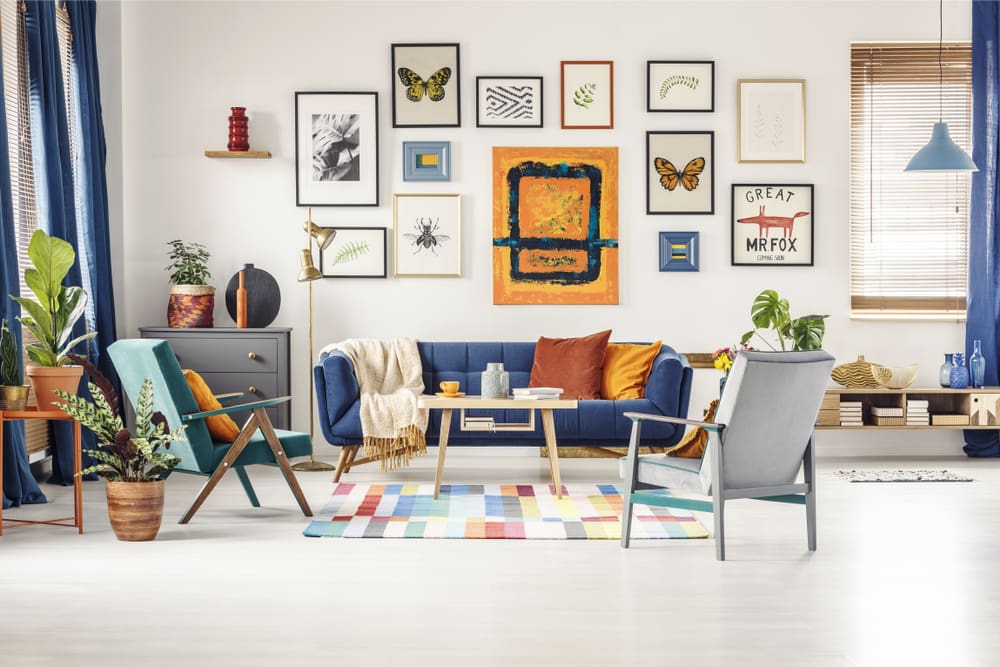 Photo of a bright living room with a gallery wall featuring different types of artwork. Featured Image for How to Create a Gallery Wall.