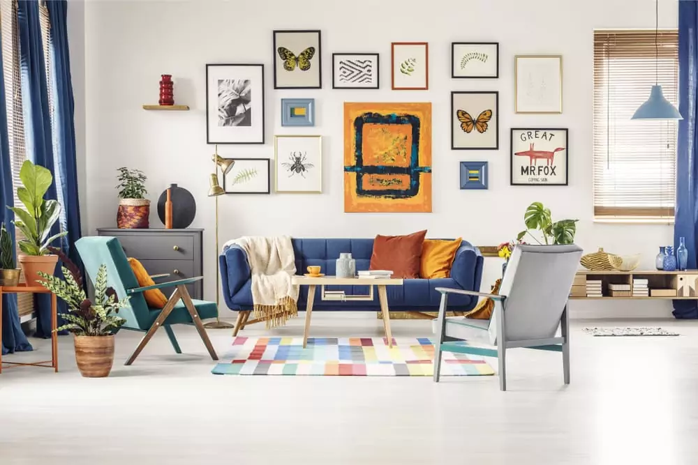 Photo of a bright living room with a gallery wall featuring different types of artwork. Featured Image for How to Create a Gallery Wall.