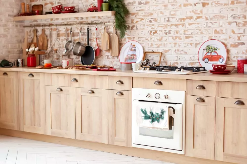 Light wood cabinets and brick-walled kitchen with Christmas decorations.