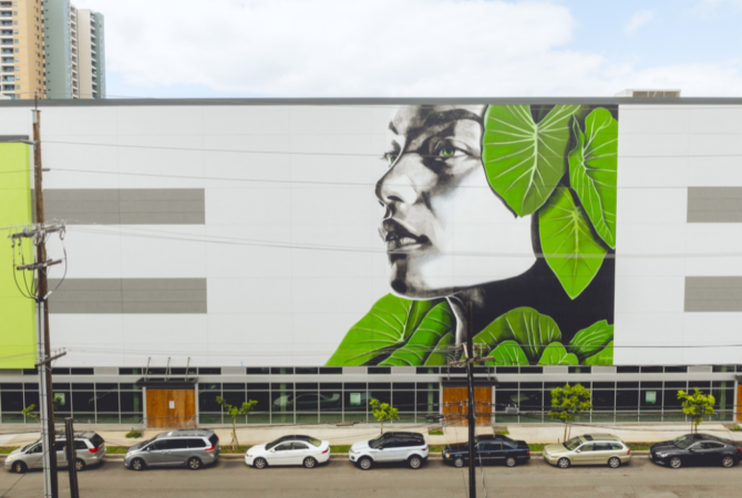 Hawaain-themed mural of female's profile in black and white surrounded by green leaves
