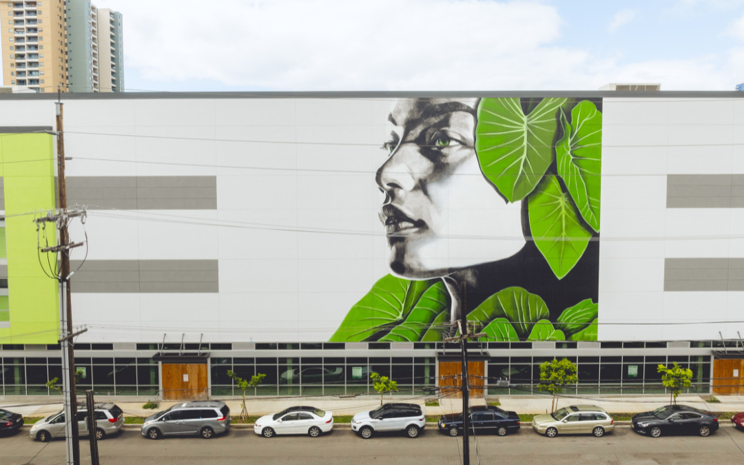 Hawaain-themed mural of female's profile in black and white surrounded by green leaves