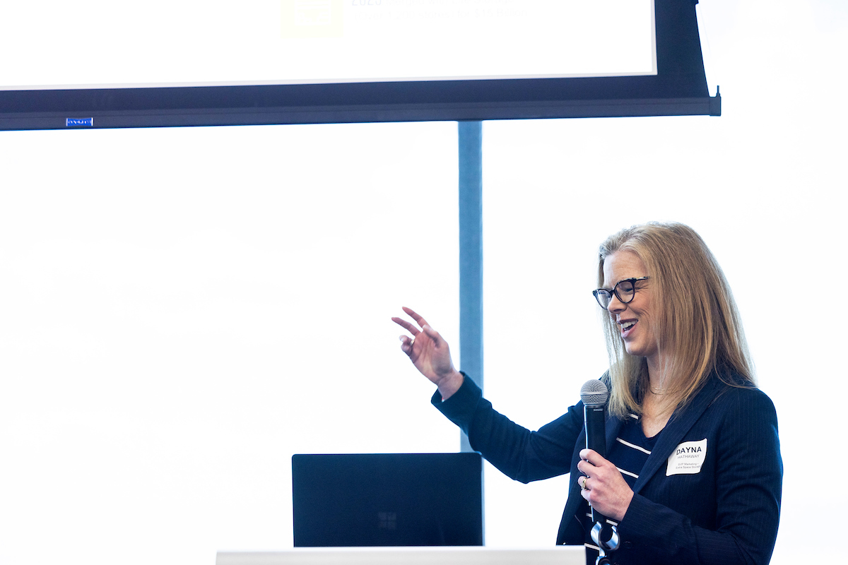 Woman gesturing with right hand while holding a microphone and lecturing