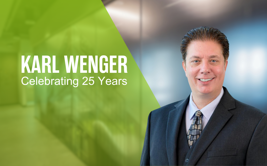 Karl Wenger smiling in black suit and tie in front of a blurred background and green overlay with his name and "celebrating 25 years" text to the left