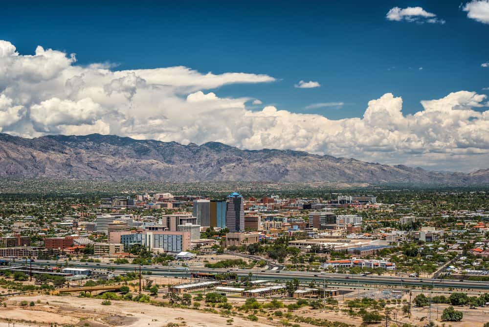 A skyline photo of Tucson showcasing some buildings in the background and the desert region around them.