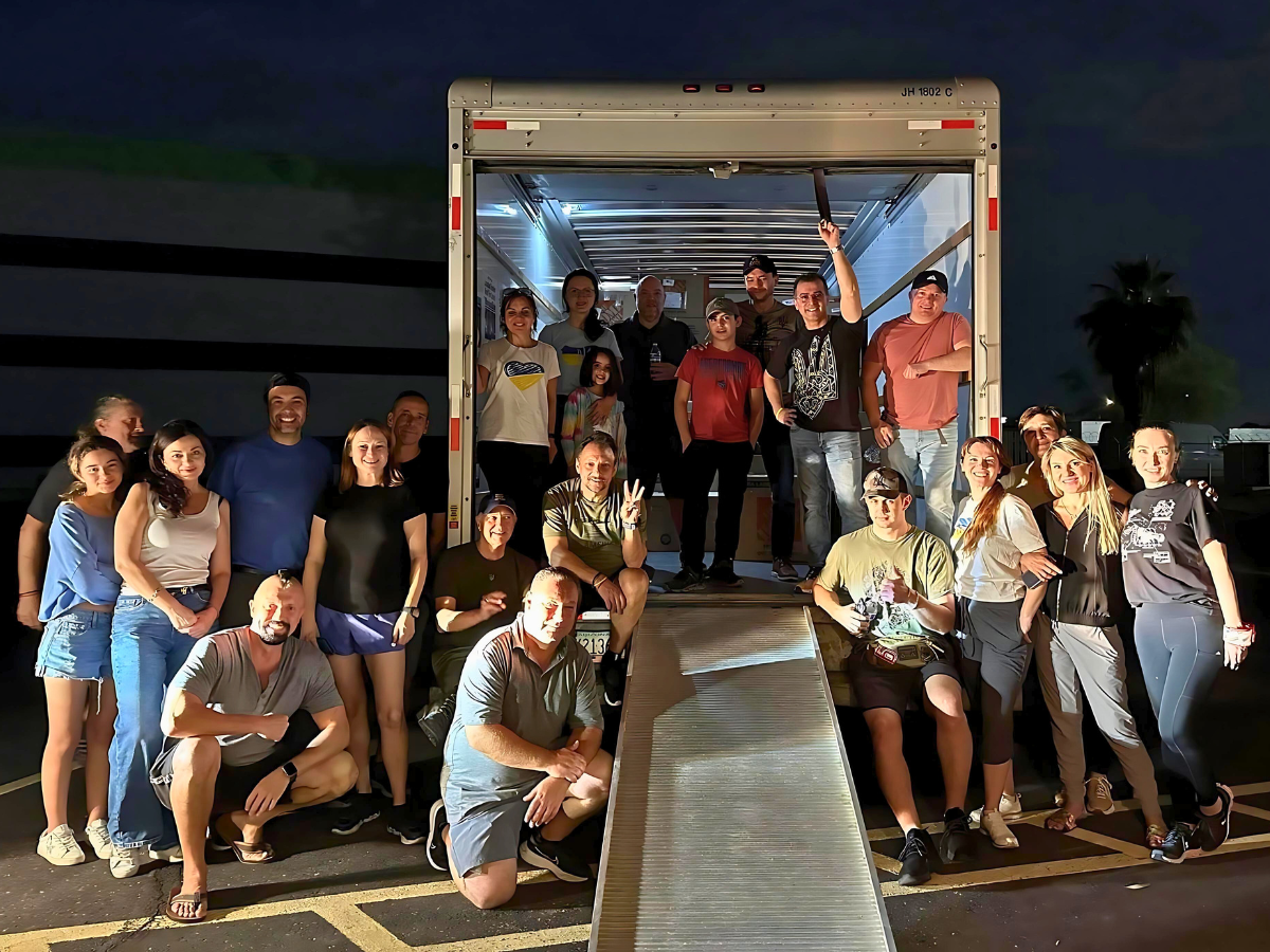 Group of 23 Central Park Angels volunteers posing in and around box truck parked in a loading bay