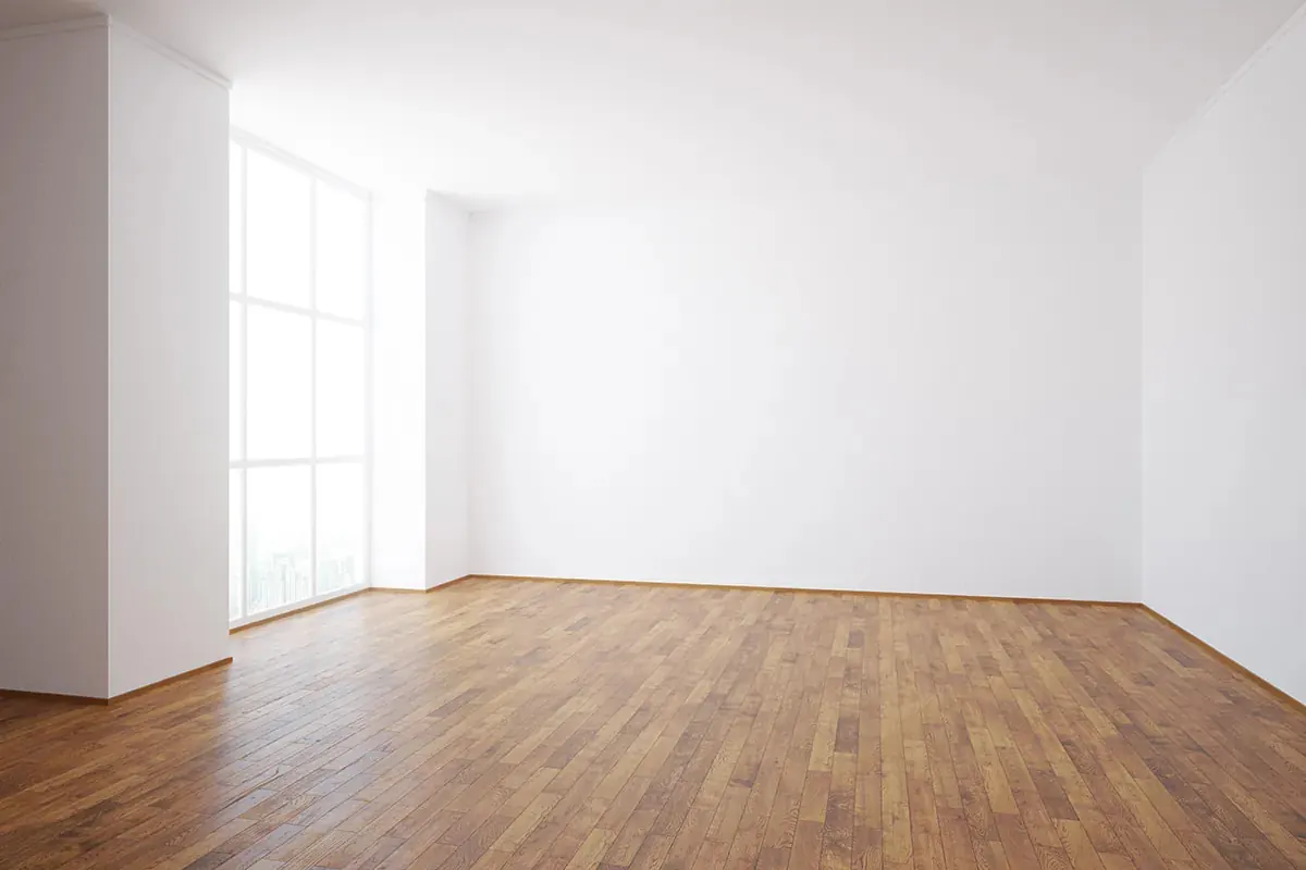 An empty, unfurnished interior room with a wooden floor, floor-to-ceiling windows with daylight coming in.