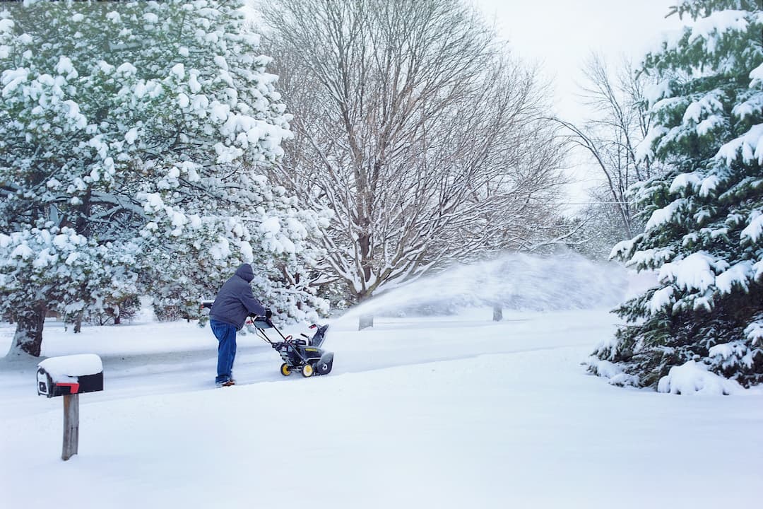 Person using snowblower to clear snow from driveway