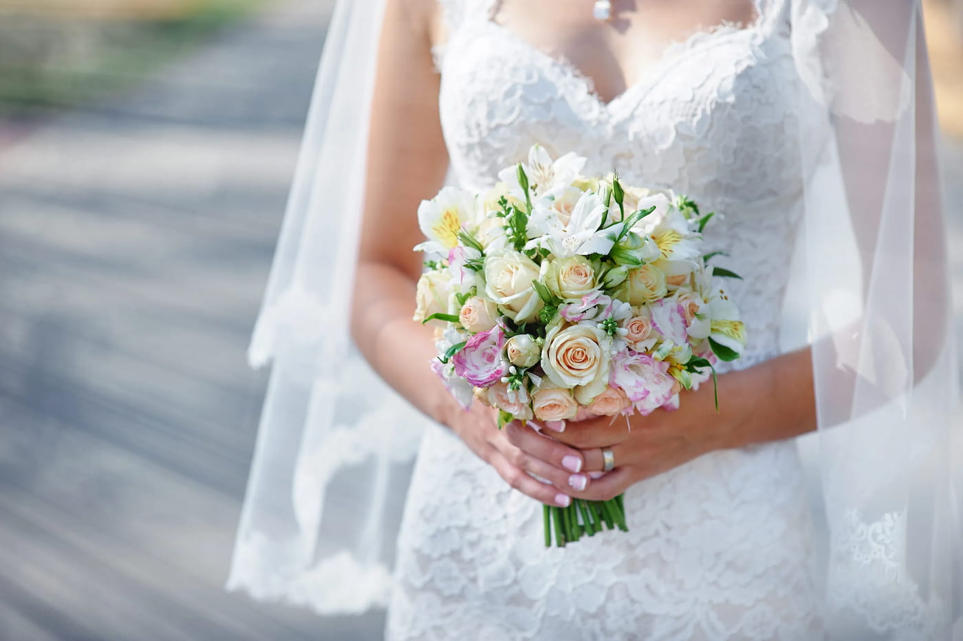 A bride holds a bouquet of roses.