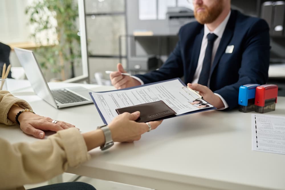Two people discussing immigration papers over a desk in an offiice