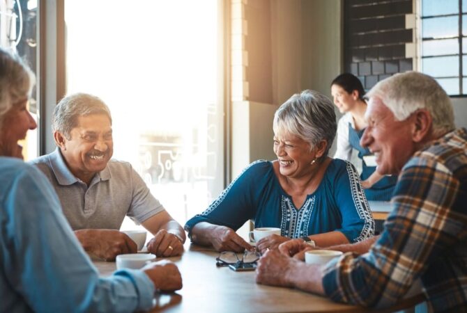 A group of retirees smiling during a conversation over coffee