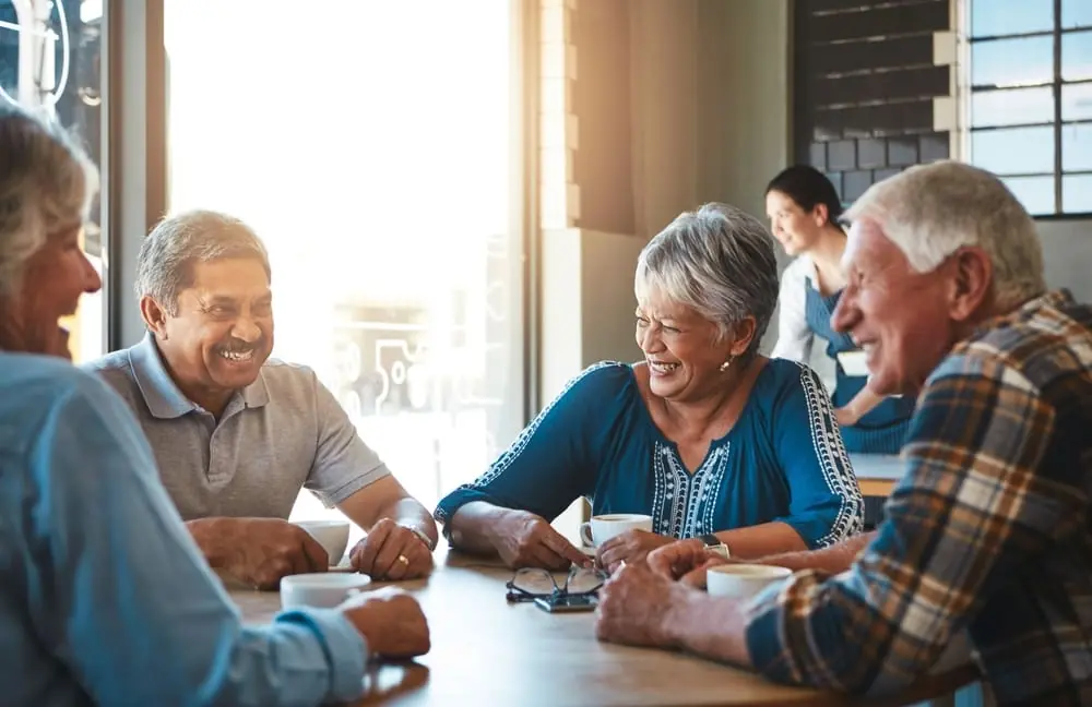 A group of retirees smiling during a conversation over coffee
