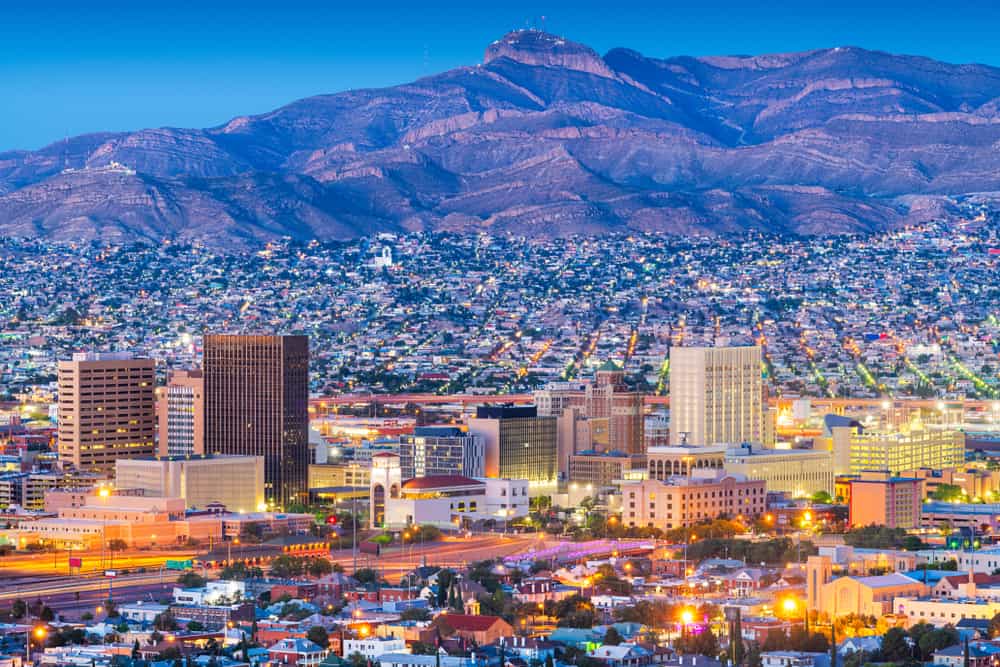 El Paso's skyline at dusk with city lights shining and the mountains in the background.