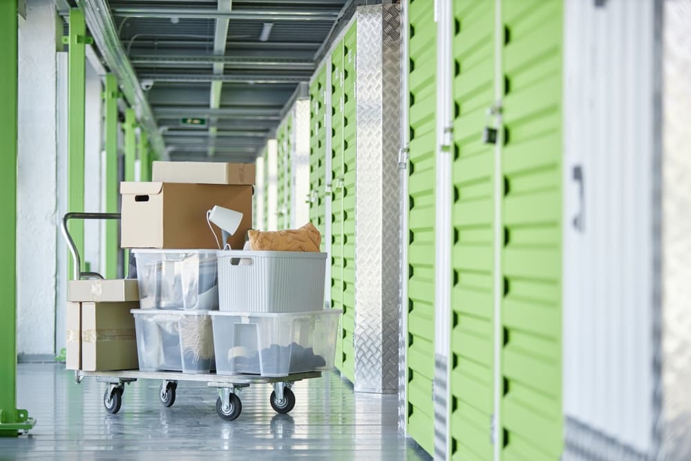 Internal hallway of a self storage unit with a cart of boxes and locked door making it unsafe to live in a storage unit