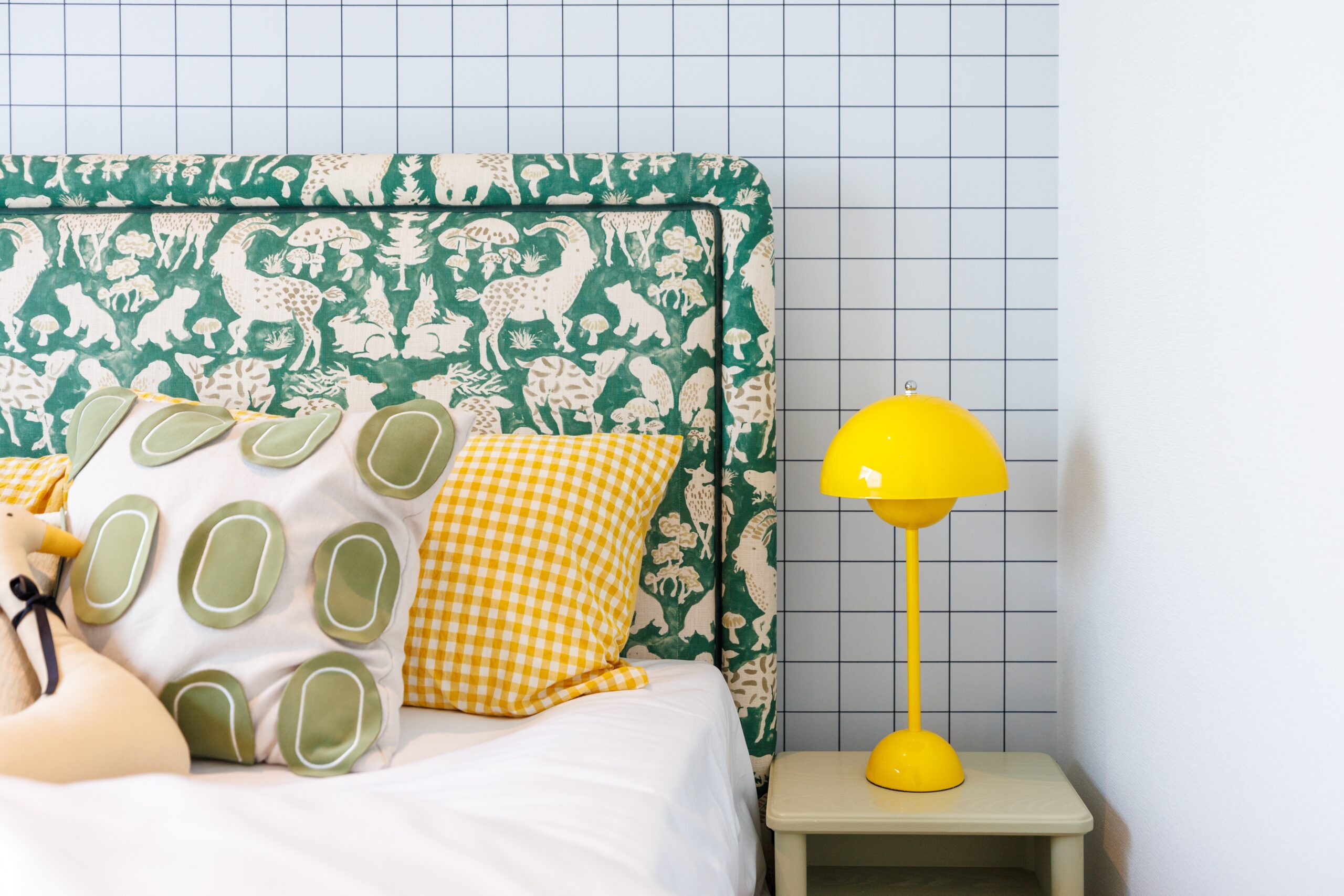 A bedroom with brightly colored pillows and a yellow lamp