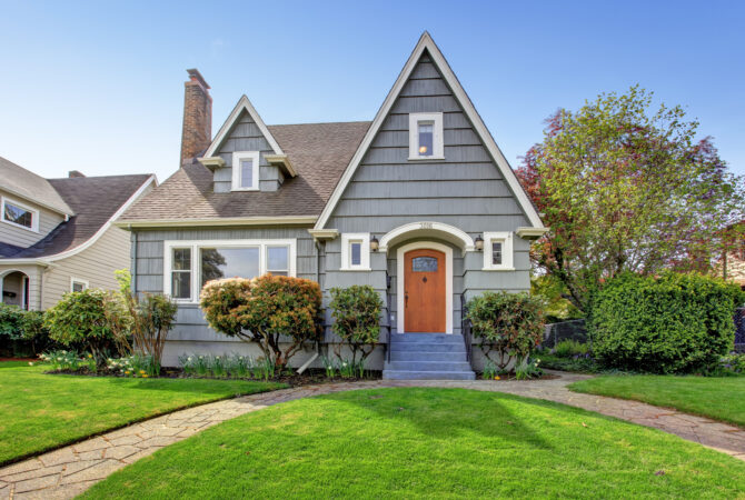 a grey house with brown front door and green grass