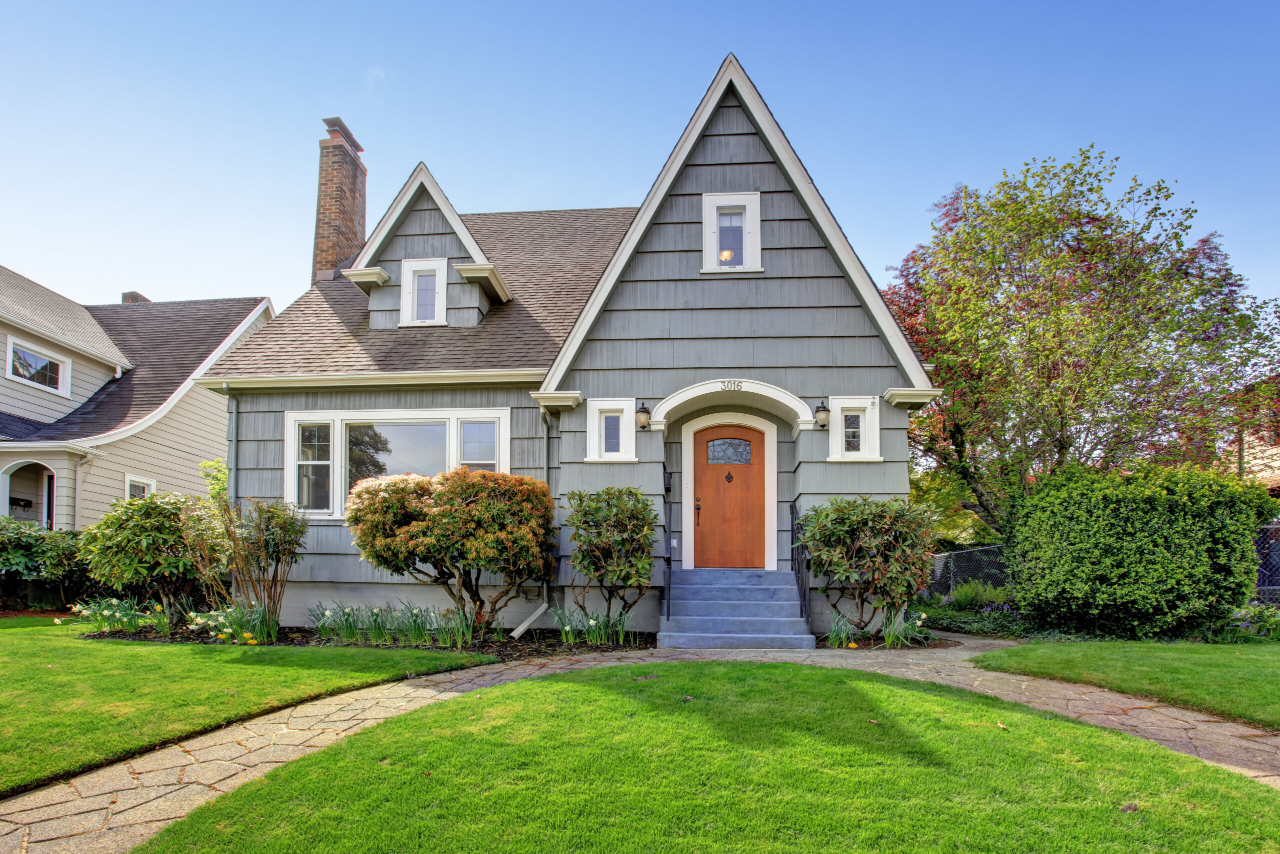 a grey house with brown front door and green grass