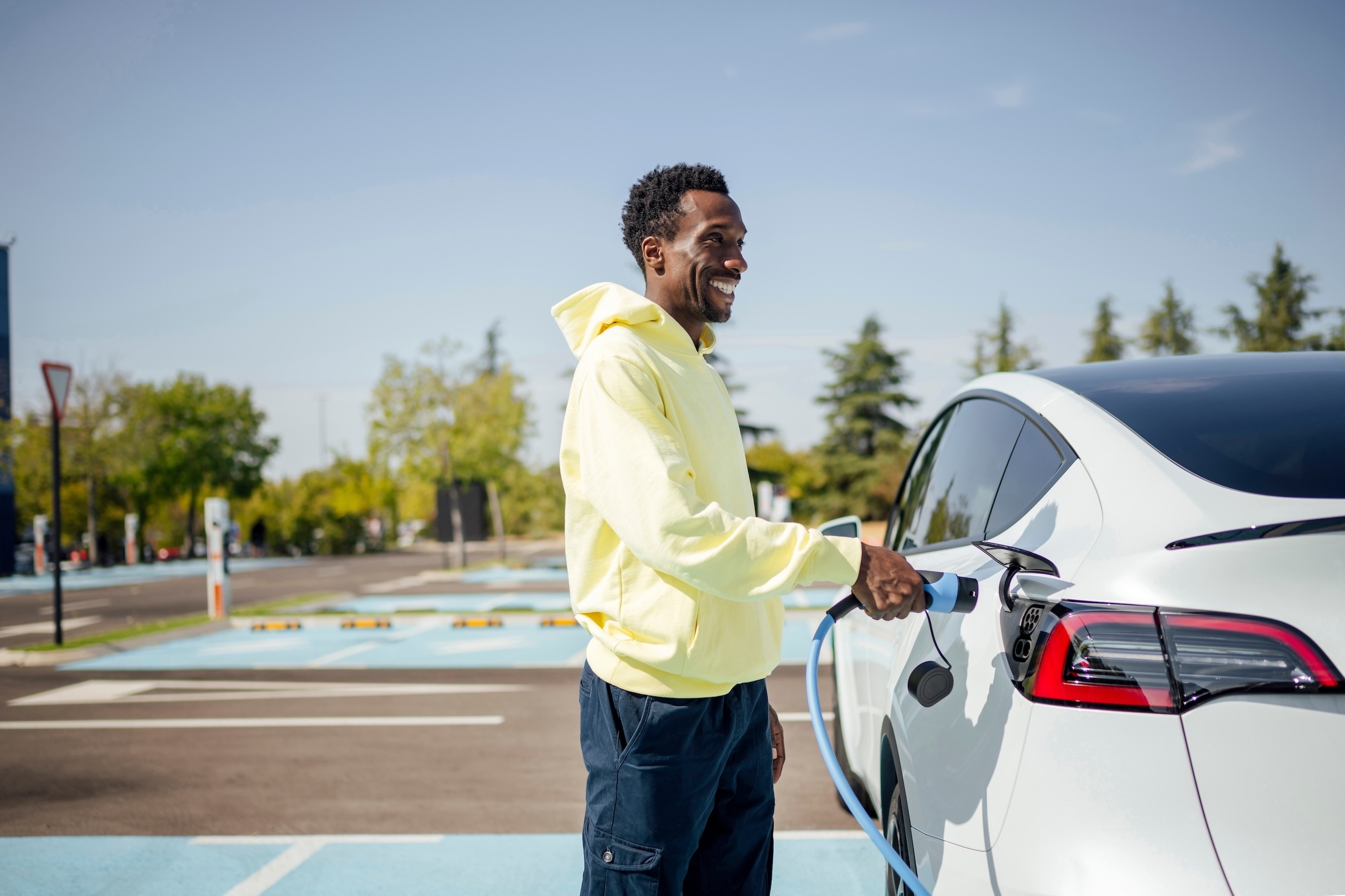 A man smiling while charging his car in a sustainable US city