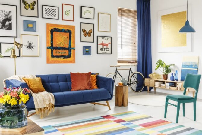 A colorful living room featuring a blue couch with a gallery wall behind it