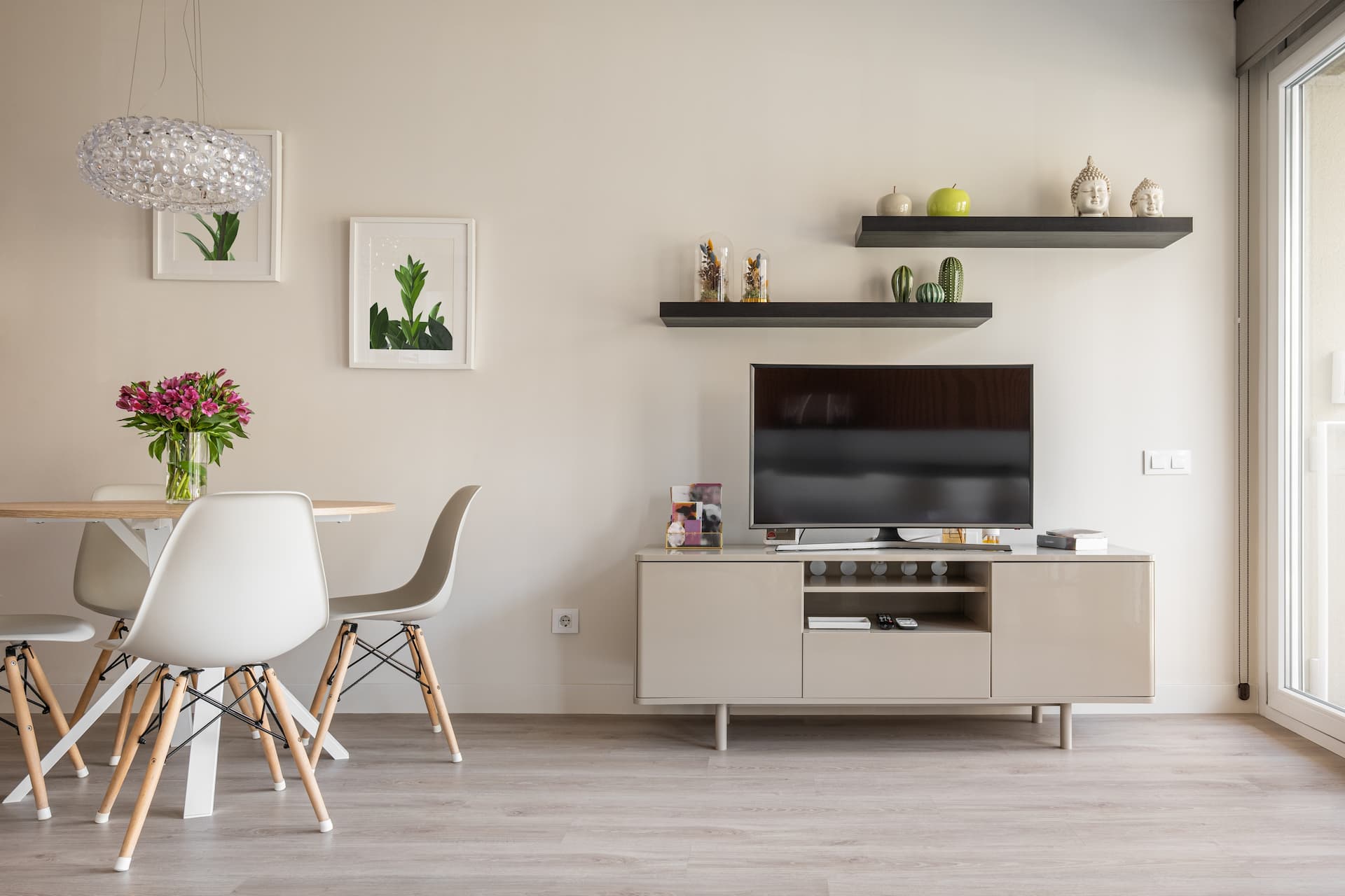 A clean living room with a Tv sand with some floating shelves with decor above the tv.